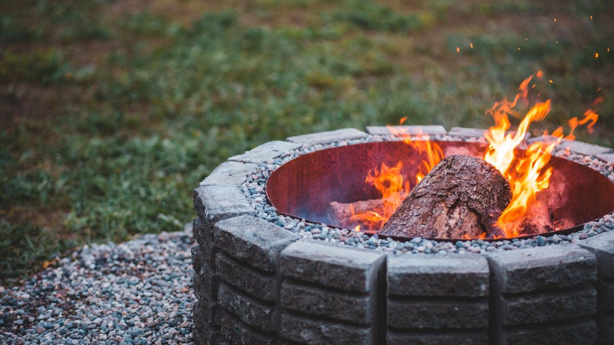 Brasero artisanal en acier dans un jardin avec feu allumé