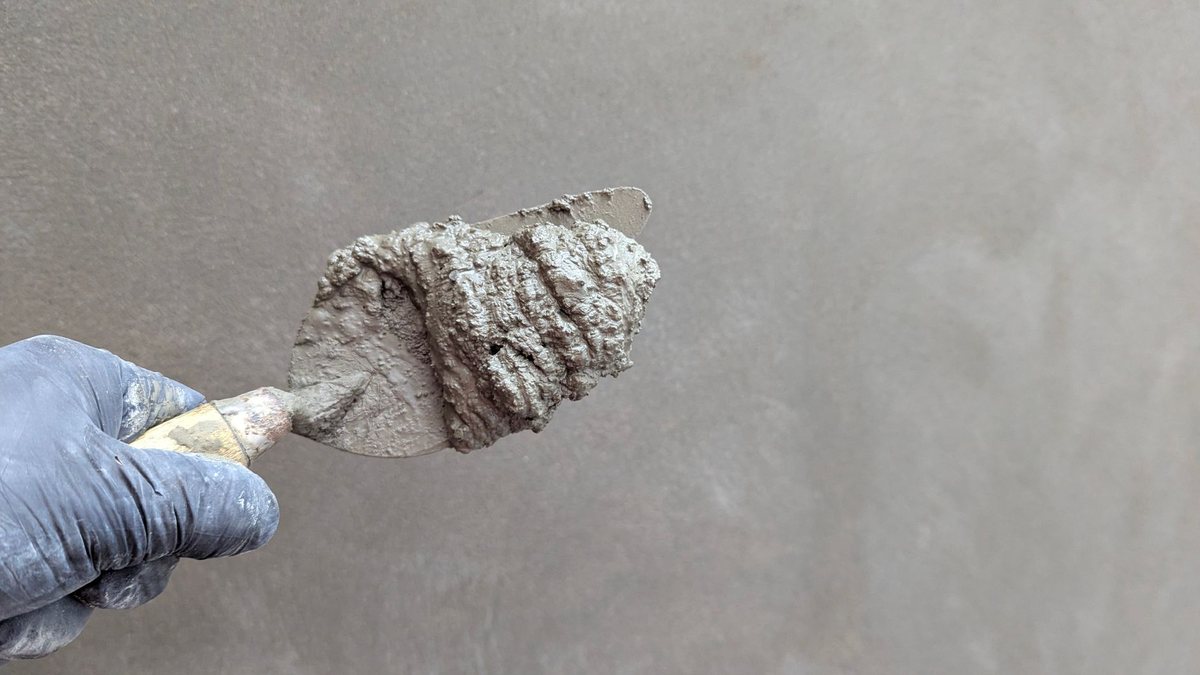 Artisan lissant un mur avec une lisseuse large